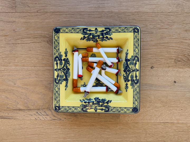 Murano glass cigarettes in a yellow and blue porcelain tray, overhead view