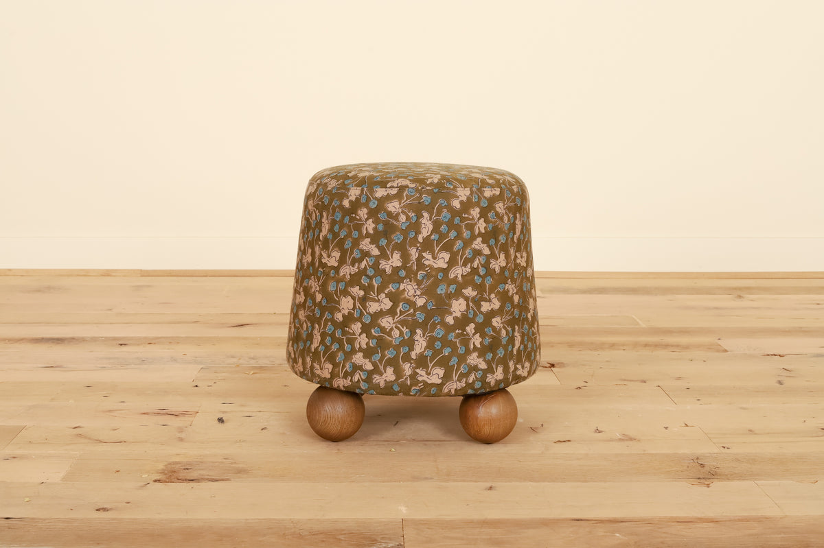 Flavia Ottoman in Allem Studio, front view on a wood floor
