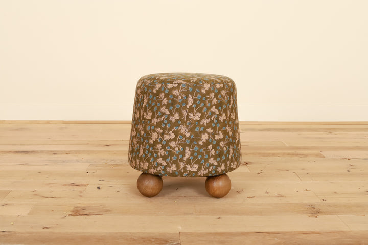 Flavia Ottoman in Allem Studio, front view on a wood floor