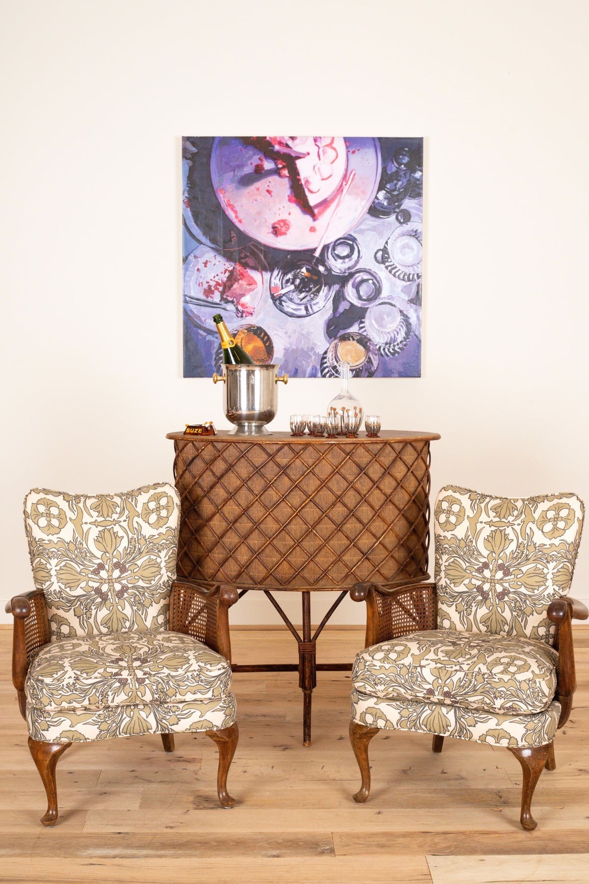 Pair of French sculptural armchairs with cane sides, styled with a rattan bar cabinet